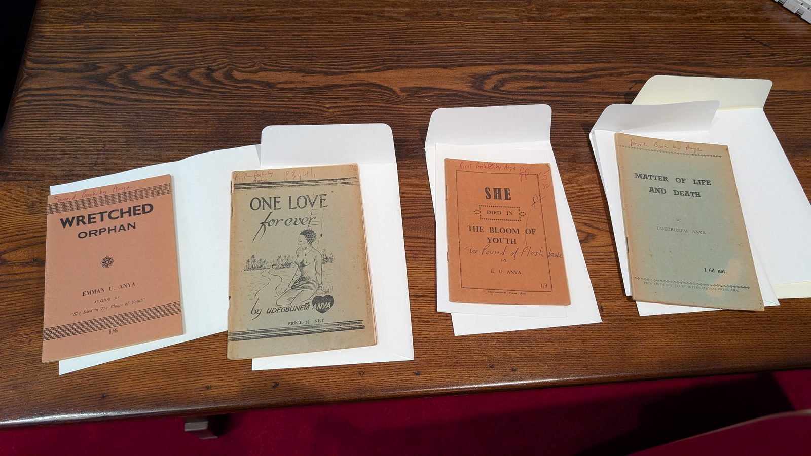 Four Onitsha pamphlets by Udegbunem Anya laid out on a reading-room table in protective envelopes