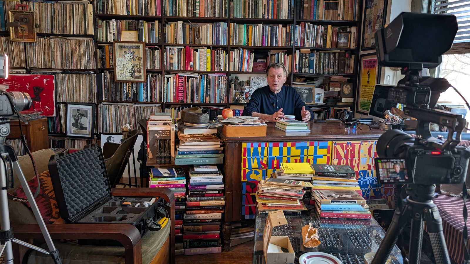 Kurt Thometz seated at his desk surrounded by floor-to-ceiling shelves of books and records