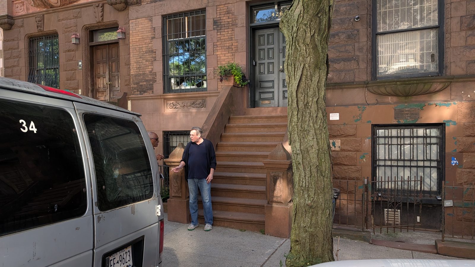 Kurt Thometz standing on the pavement outside a Harlem brownstone