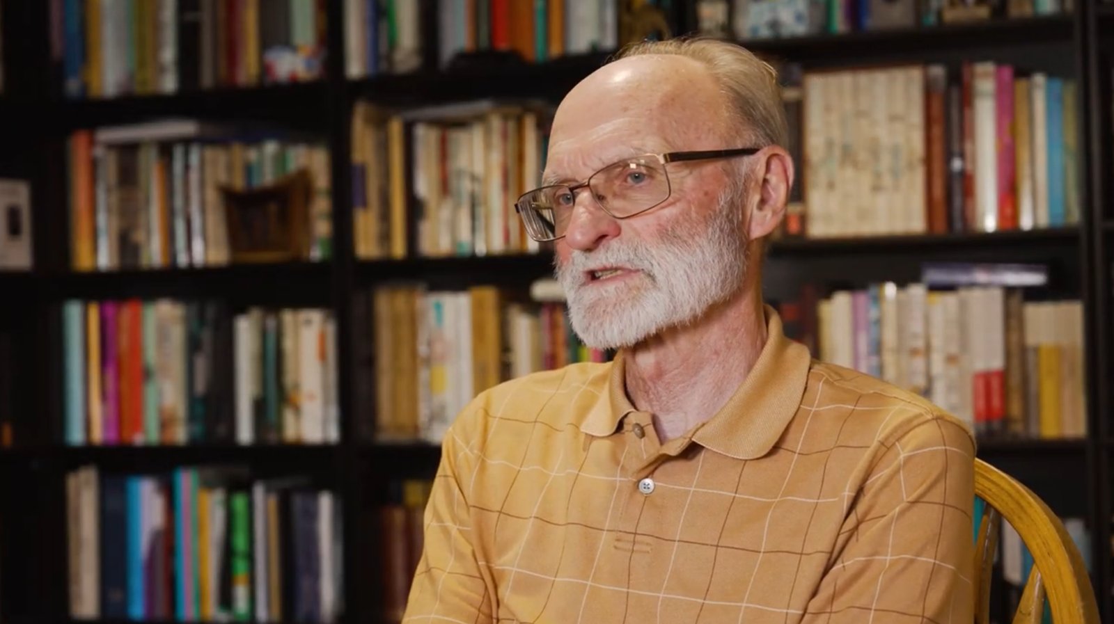 Ronald P. Schaefer seated in front of full bookshelves during his filmed interview